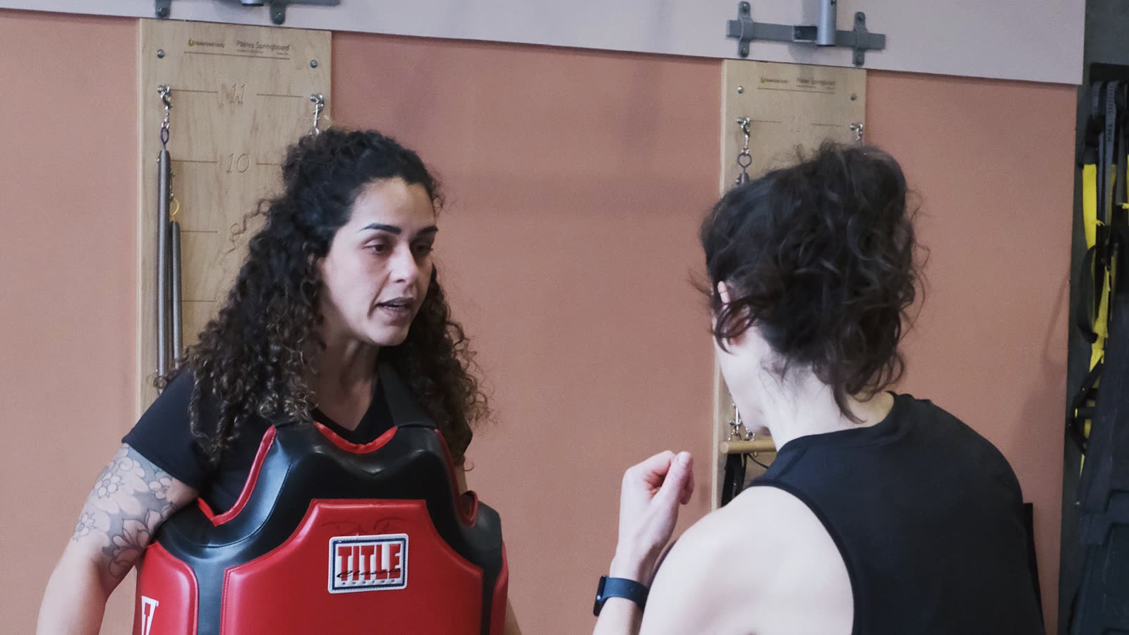 Female student practicing high kick on pad with Fabi